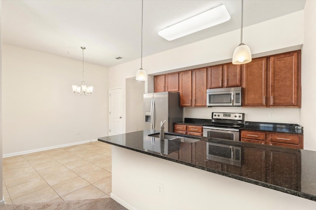 kitchen featuring appliances with stainless steel finishes, sink, dark stone counters, and decorative light fixtures