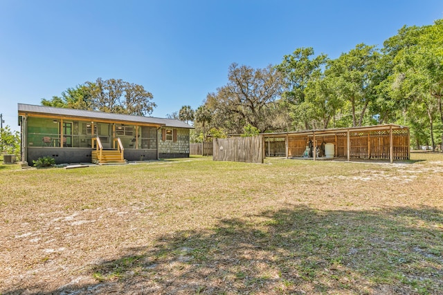back of house featuring a lawn, a carport, and metal roof