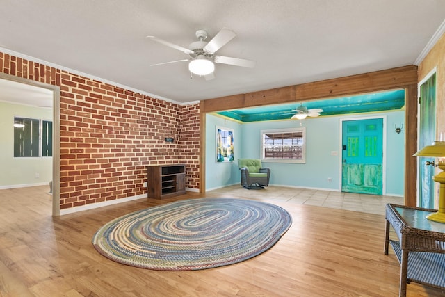 unfurnished living room with baseboards, a ceiling fan, wood finished floors, and crown molding