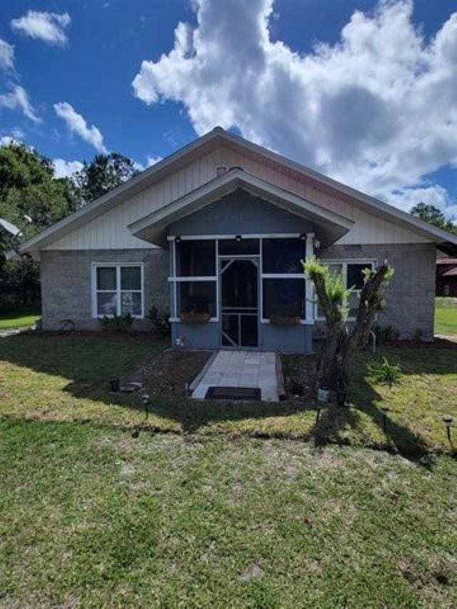 back of property with a sunroom and a yard