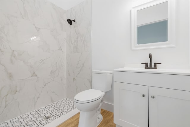 bathroom featuring toilet, hardwood / wood-style floors, vanity, and a tile shower