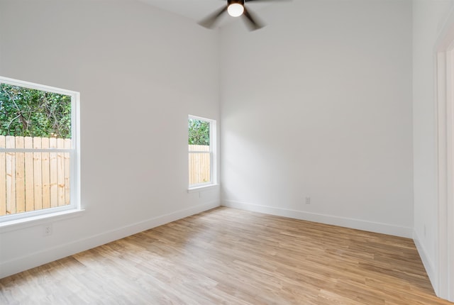 empty room featuring light wood-type flooring, ceiling fan, and a healthy amount of sunlight