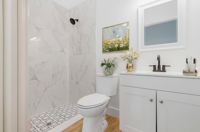 bathroom featuring a tile shower, toilet, vanity, and hardwood / wood-style flooring