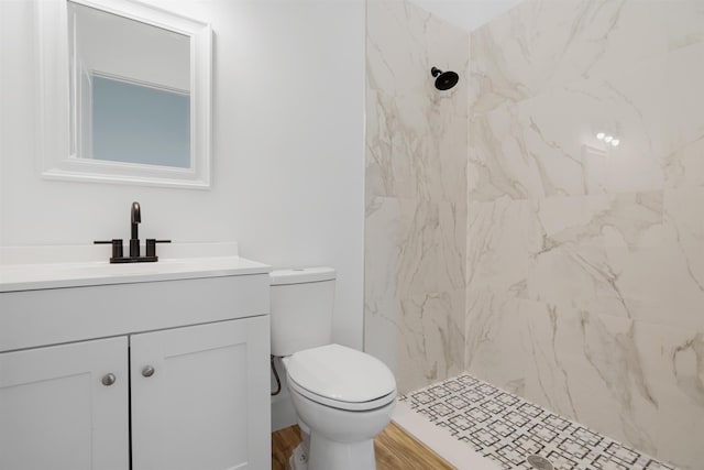 bathroom featuring hardwood / wood-style floors, vanity, toilet, and tiled shower