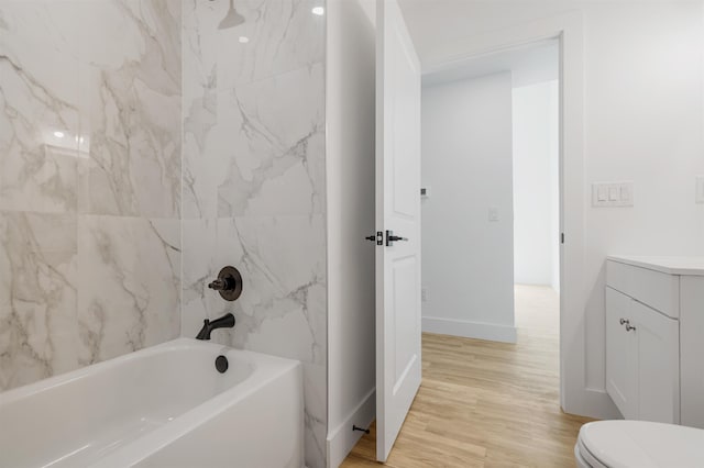 full bathroom featuring tiled shower / bath combo, toilet, wood-type flooring, and vanity