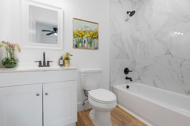 full bathroom with hardwood / wood-style floors, vanity, tiled shower / bath combo, ceiling fan, and toilet