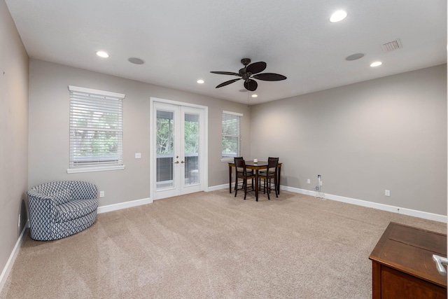 living area featuring ceiling fan, light colored carpet, and french doors