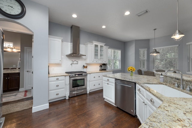 kitchen featuring white cabinets, wall chimney range hood, sink, dark hardwood / wood-style flooring, and stainless steel appliances