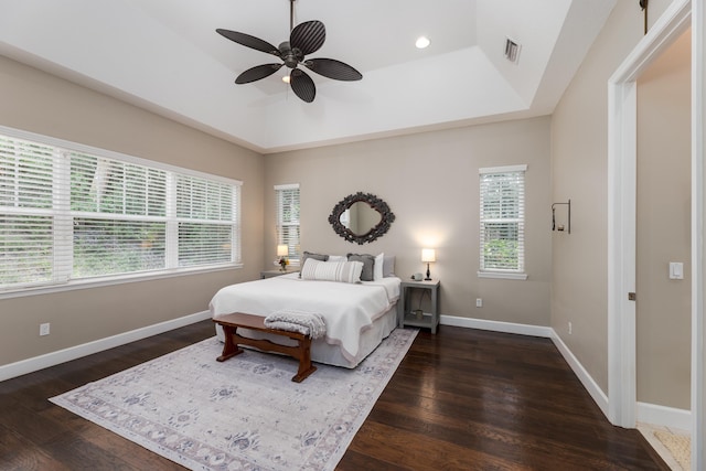 bedroom with dark hardwood / wood-style floors, a raised ceiling, and ceiling fan