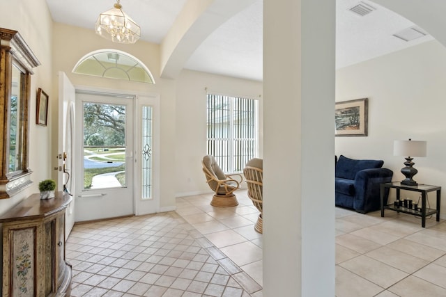 foyer with light tile patterned floors, plenty of natural light, visible vents, and arched walkways