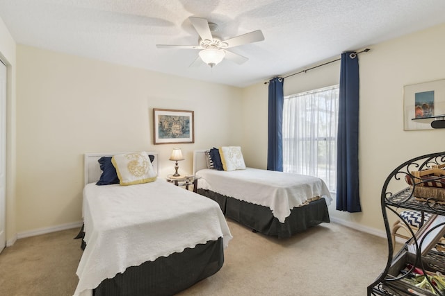 bedroom featuring light carpet, baseboards, a ceiling fan, and a textured ceiling