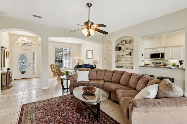 living room featuring built in features, visible vents, light tile patterned flooring, ceiling fan, and baseboards