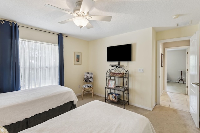 bedroom with visible vents, light carpet, ceiling fan, and a textured ceiling