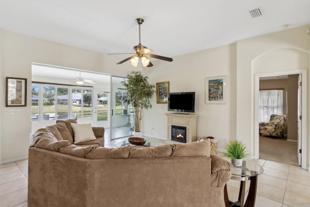 living room with a glass covered fireplace, visible vents, plenty of natural light, and light tile patterned flooring