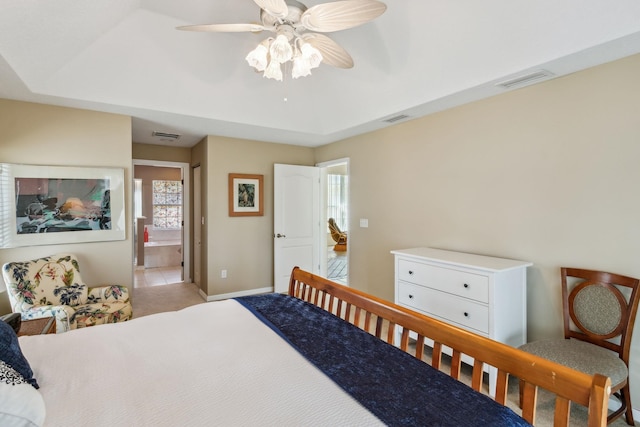 bedroom with a tray ceiling, visible vents, and baseboards