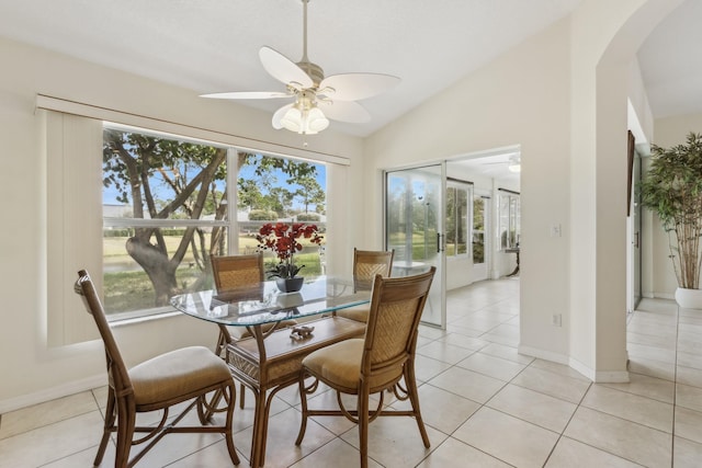 dining area with light tile patterned floors, ceiling fan, arched walkways, and vaulted ceiling