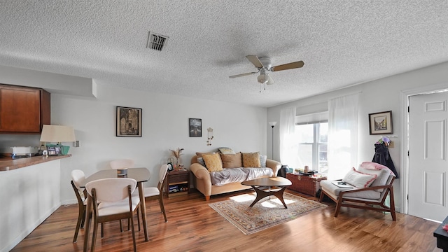 living room with a textured ceiling, ceiling fan, and dark hardwood / wood-style flooring