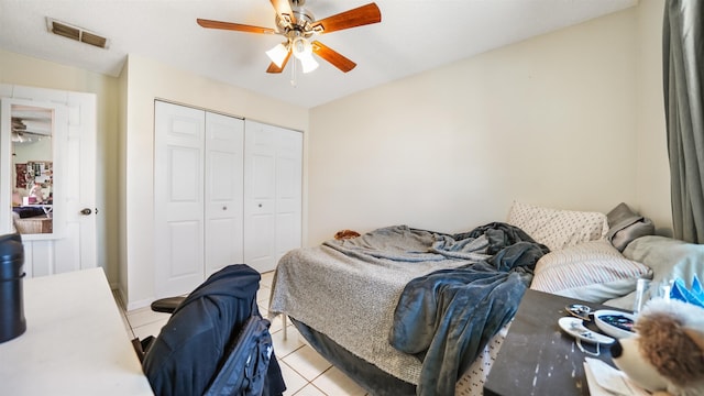 bedroom with ceiling fan, light tile patterned floors, and a closet