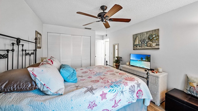 bedroom featuring a textured ceiling, ceiling fan, a closet, and wood-type flooring