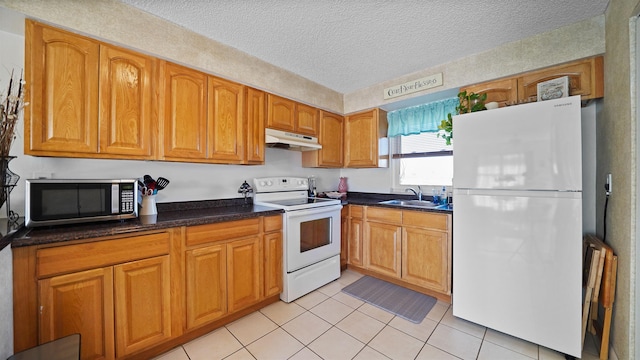 kitchen featuring light tile patterned floors, sink, white appliances, and a textured ceiling