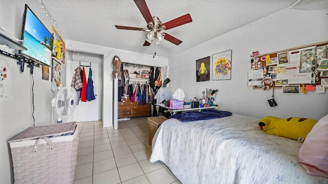 bedroom with ceiling fan, light tile patterned floors, a closet, and a textured ceiling