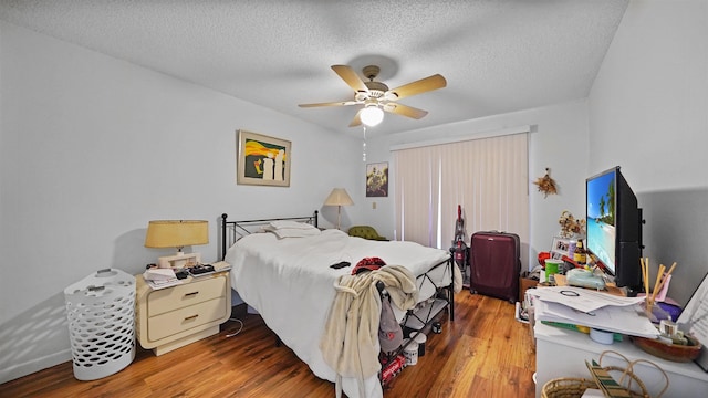 bedroom with ceiling fan, hardwood / wood-style floors, and a textured ceiling