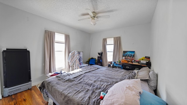 bedroom with ceiling fan, a textured ceiling, and hardwood / wood-style flooring