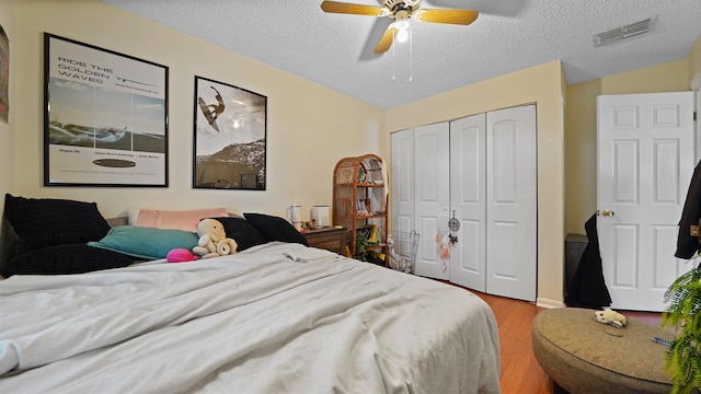 bedroom featuring ceiling fan, wood-type flooring, a closet, and a textured ceiling