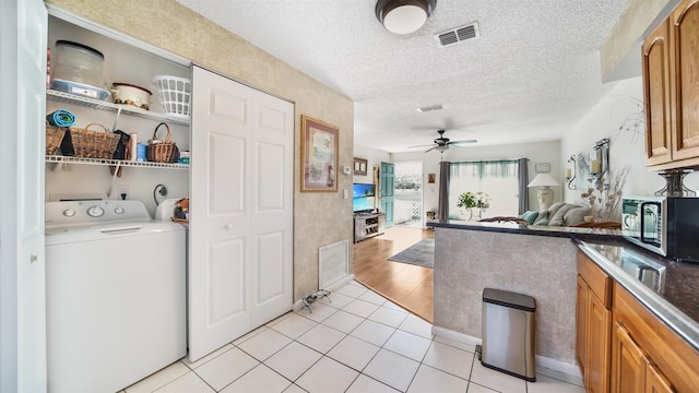 interior space featuring ceiling fan, washer / clothes dryer, light tile patterned floors, and a textured ceiling