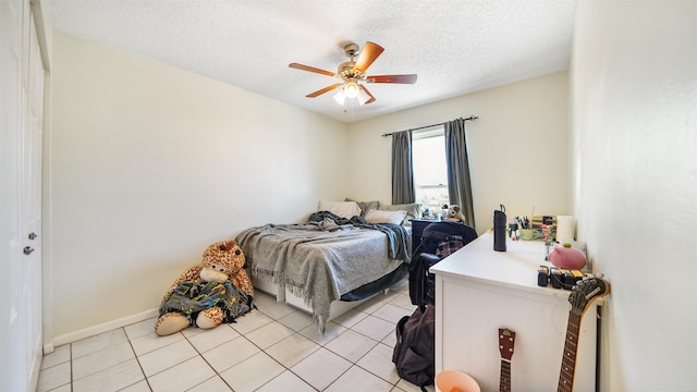 bedroom with ceiling fan, light tile patterned floors, and a textured ceiling