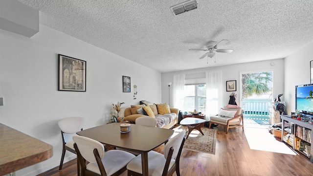 dining room with ceiling fan, dark wood-type flooring, and a textured ceiling