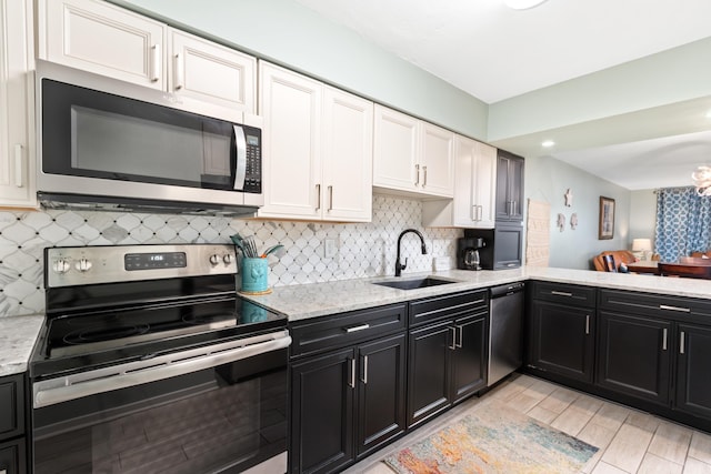 kitchen featuring light stone countertops, backsplash, stainless steel appliances, sink, and white cabinetry