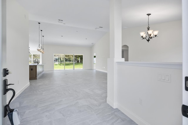 hallway featuring a notable chandelier, sink, and high vaulted ceiling