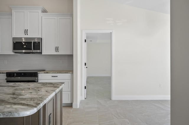 kitchen with light tile patterned floors, light stone countertops, white cabinetry, and black range with electric cooktop