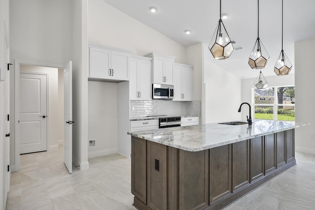 kitchen with pendant lighting, white cabinets, sink, light stone countertops, and stainless steel appliances