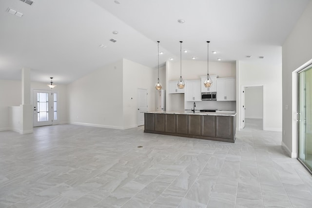 kitchen with a kitchen island with sink, high vaulted ceiling, sink, hanging light fixtures, and white cabinetry