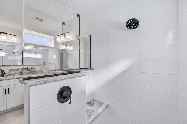 bathroom with a tile shower and vanity