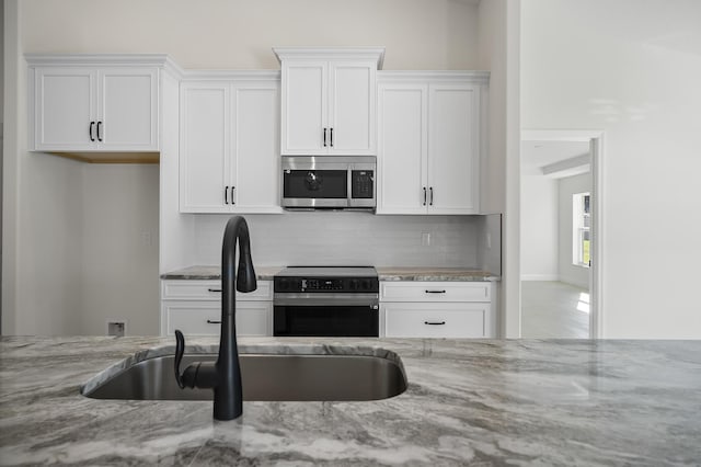 kitchen with white cabinetry, light stone countertops, and appliances with stainless steel finishes