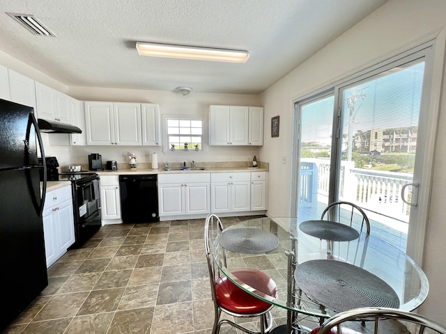 5961 S A1A, Saint Augustine, FL 32080 - kitchen featuring black appliances, under cabinet range hood, white cabinetry, light countertops, and stone finish floors
