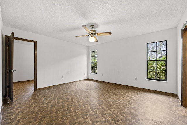 empty room featuring a wealth of natural light, ceiling fan, and a textured ceiling