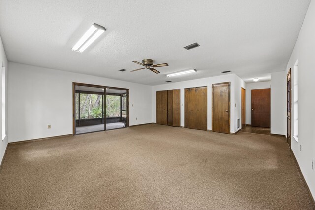 carpeted spare room featuring a textured ceiling and ceiling fan