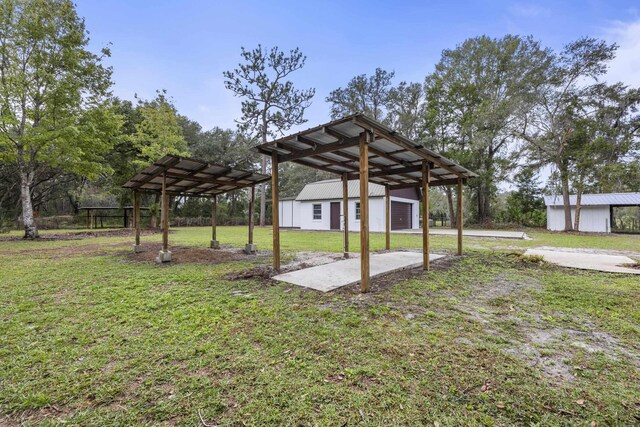 view of yard featuring a garage, a carport, and an outdoor structure