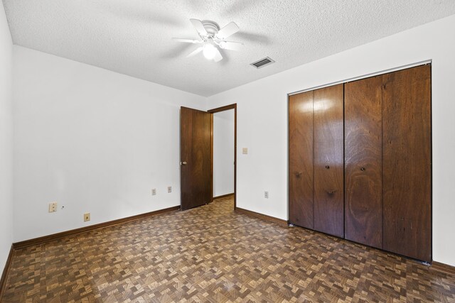 unfurnished bedroom featuring ceiling fan, dark parquet flooring, and a textured ceiling