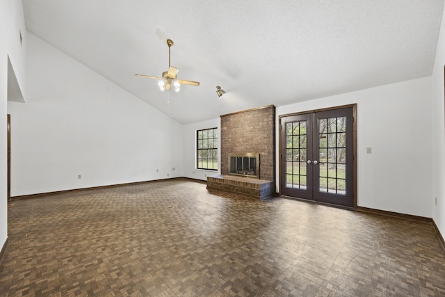 unfurnished living room featuring high vaulted ceiling, french doors, ceiling fan, a textured ceiling, and a fireplace