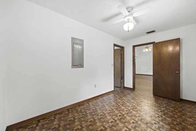 interior space featuring ceiling fan, dark parquet flooring, a textured ceiling, and electric panel