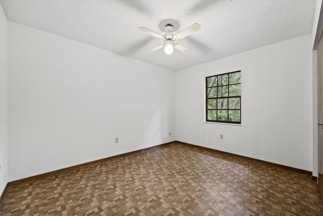 unfurnished room with ceiling fan, a textured ceiling, and dark parquet floors