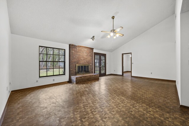 unfurnished living room with ceiling fan, a brick fireplace, dark parquet floors, high vaulted ceiling, and a textured ceiling