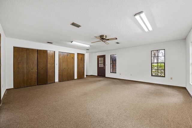 carpeted spare room featuring ceiling fan and a textured ceiling