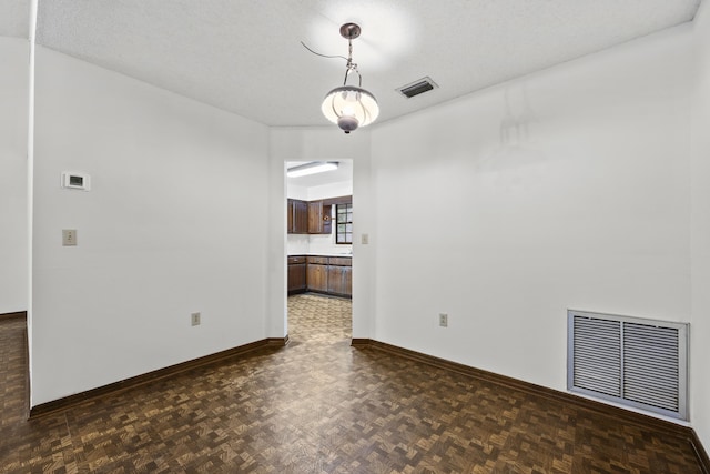 unfurnished room featuring dark parquet flooring, a textured ceiling, and a notable chandelier