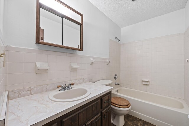 full bathroom featuring a textured ceiling, toilet, vanity, tile walls, and tiled shower / bath